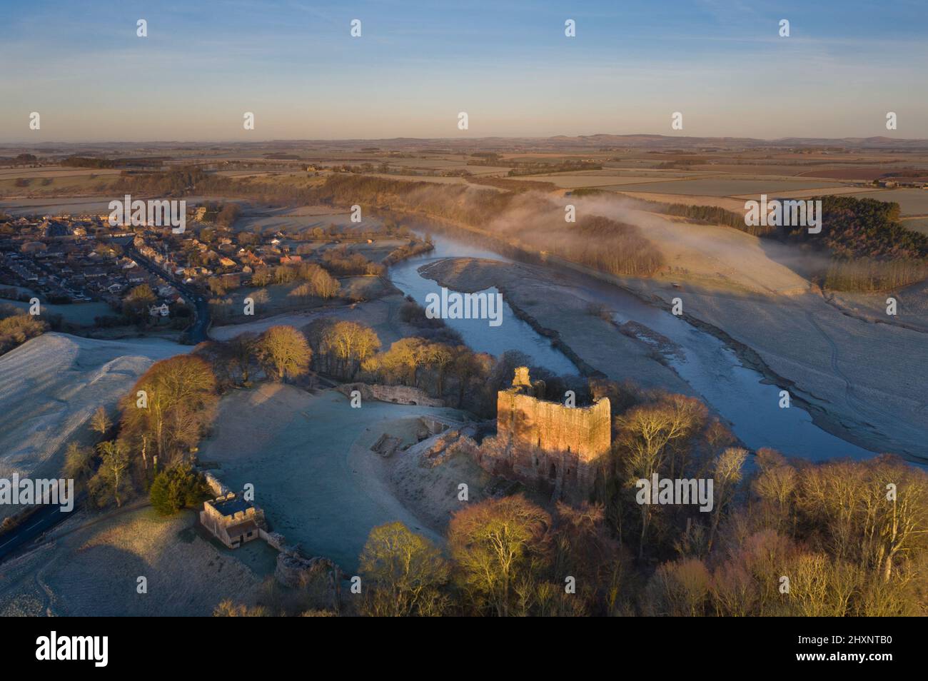 Early Morning Frosty dawn, drone view over Norham Castle, Norham village and river Tweed ,Berwick, Northumberland, England Stock Photo