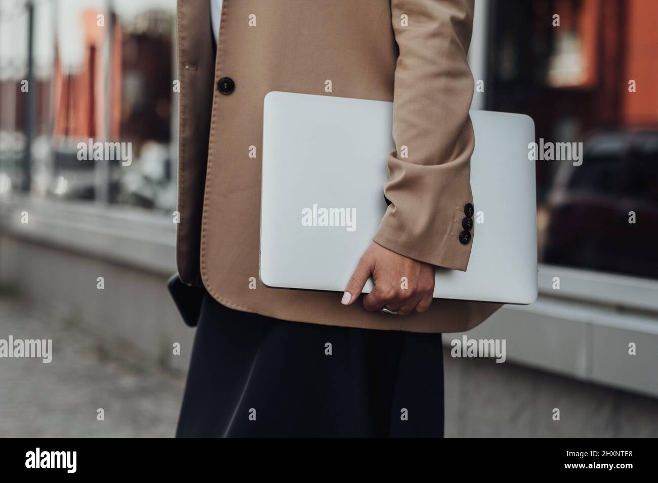 CloseUp Business Woman in a Brown Jacket Holding Laptop Outdoors Stock Photo