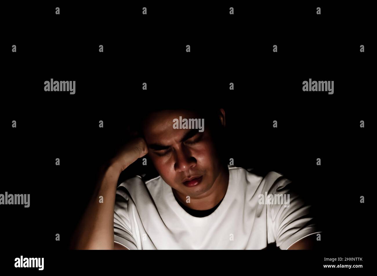 Asian miserable depressed man sitting alone in dark background. Depression and mental health concept. Stock Photo