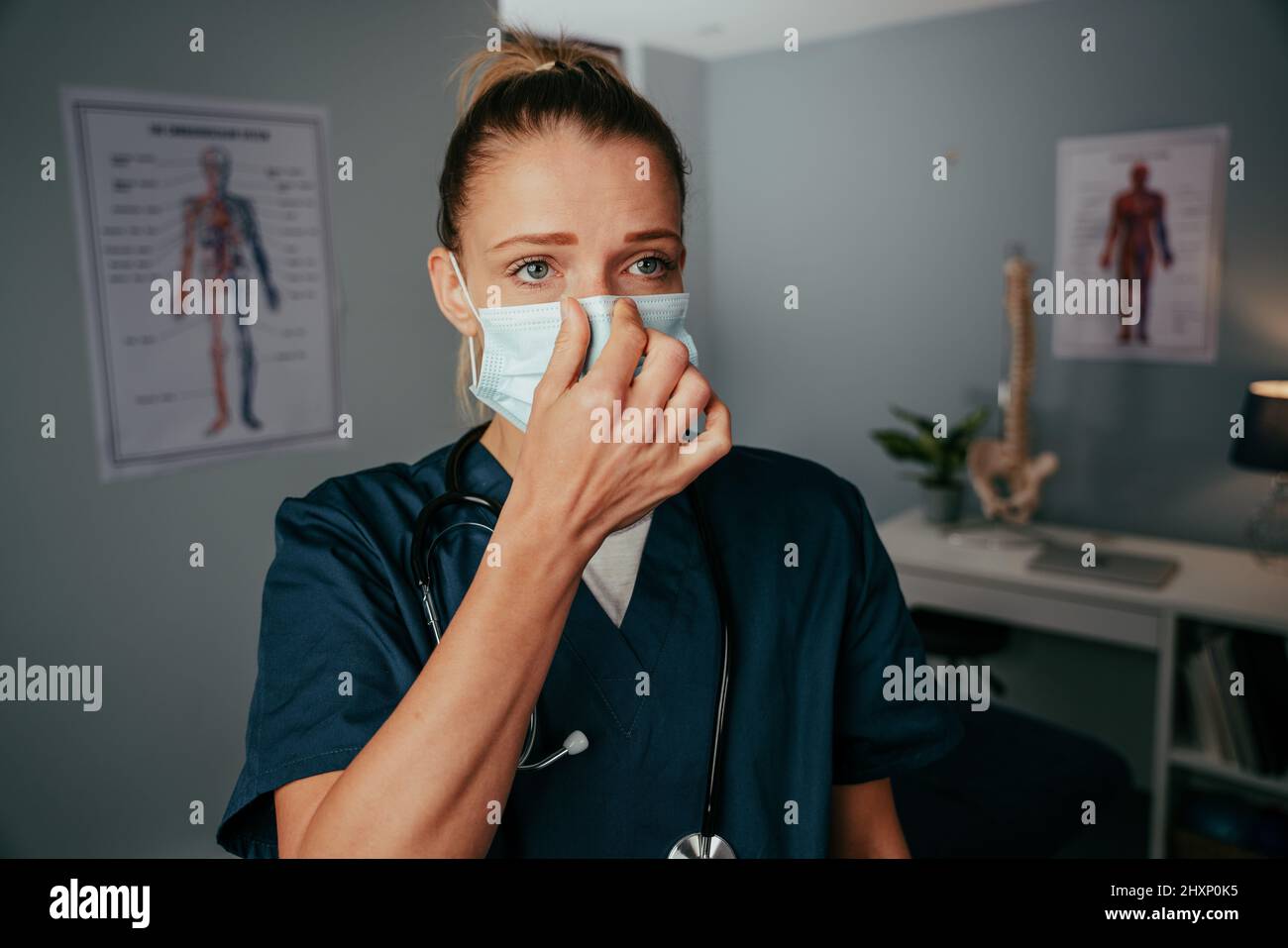 Caucasian female nurse putting on surgical mask Stock Photo