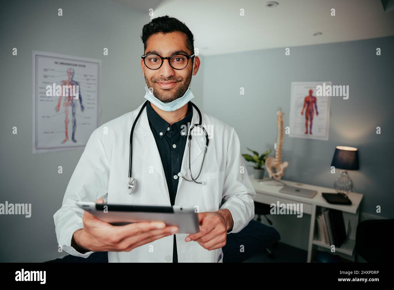 Mixed race male nurse standing in office holding digital tablet  Stock Photo
