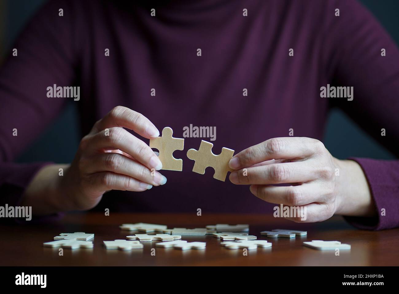Clsoe up view of woman connecting jigsaw puzzle. Team work, success or strategy concept. Stock Photo