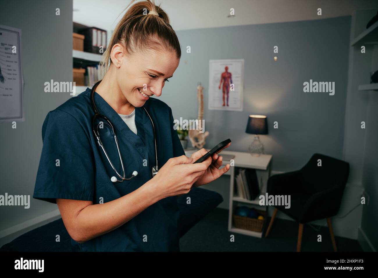 Caucasian female nurse typing on cellular device standing in doctors office Stock Photo