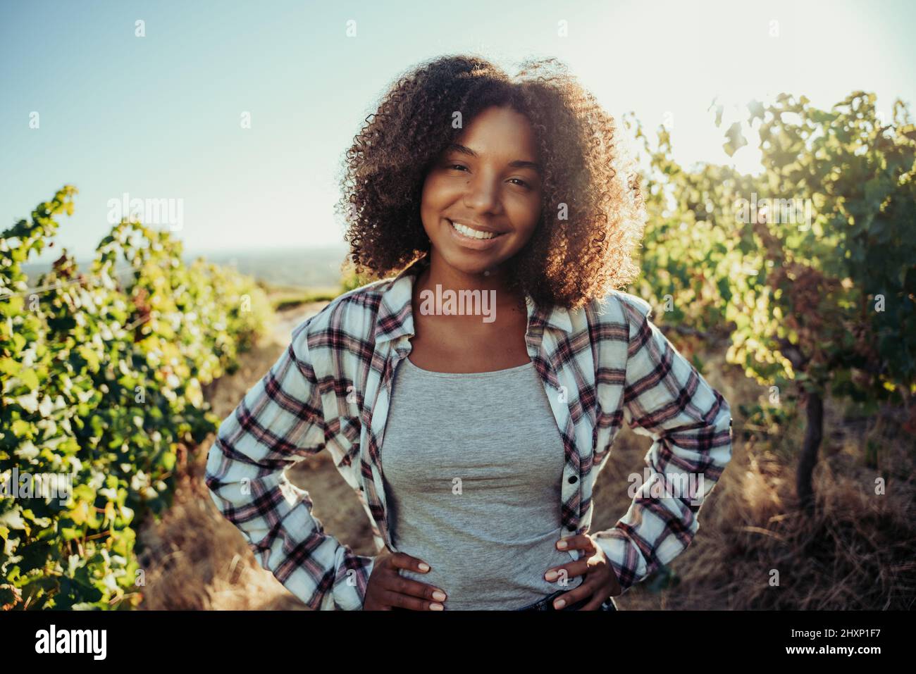 Beautiful mixed race farmer standing in vineyards with hands on hips Stock Photo