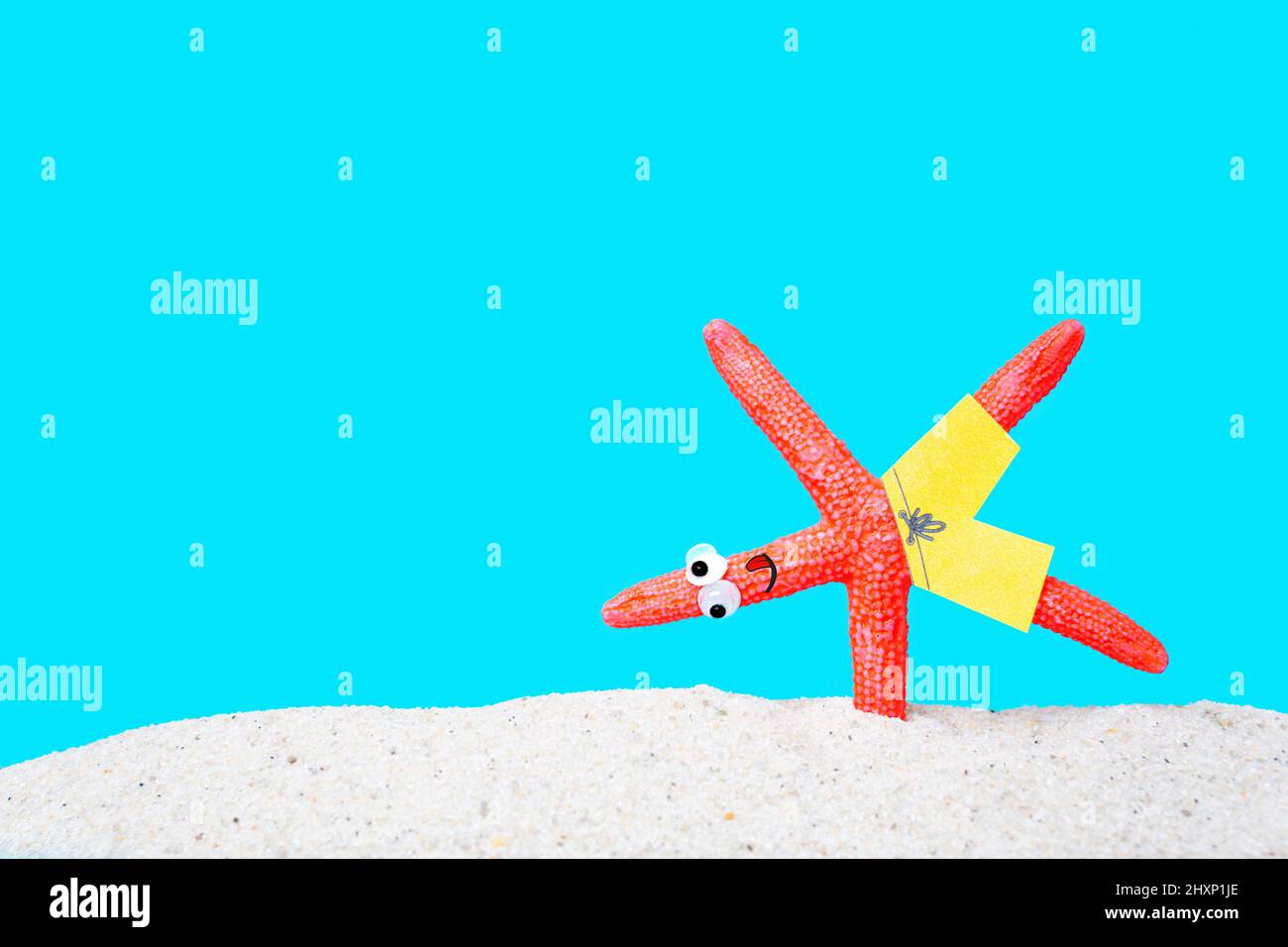 Funny starfish character making the one arm handstand on a sandy beach. Active summer vacation concept. Stock Photo