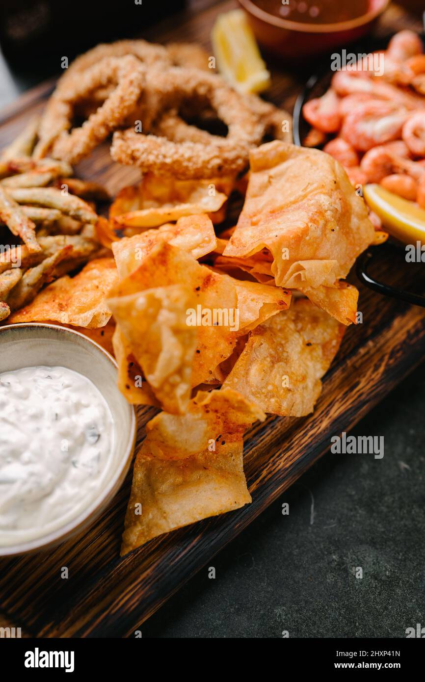 Seafood beer appetizers. Fried sprat, chips, shrimp, squid rings, lemon