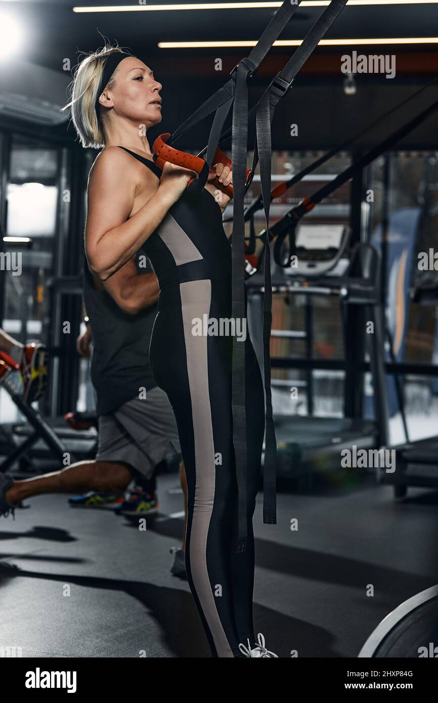 Women doing push ups training arms with trx fitness straps in the gym ...
