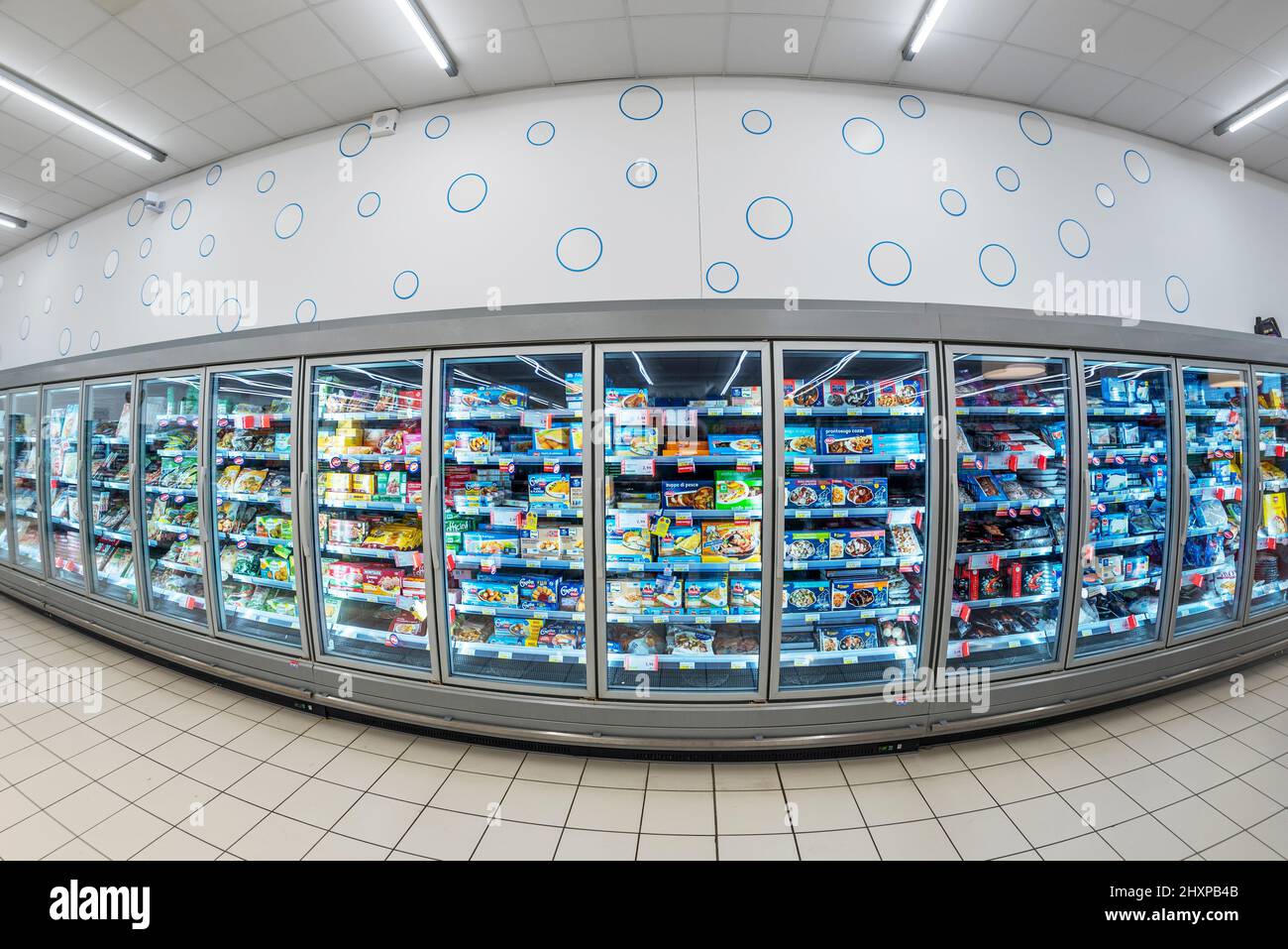 Fossano, Italy - March 12, 2022: Refrigerated showcases with frozen food packages in MERCATÒ italian supermarket, fish eye vision Stock Photo
