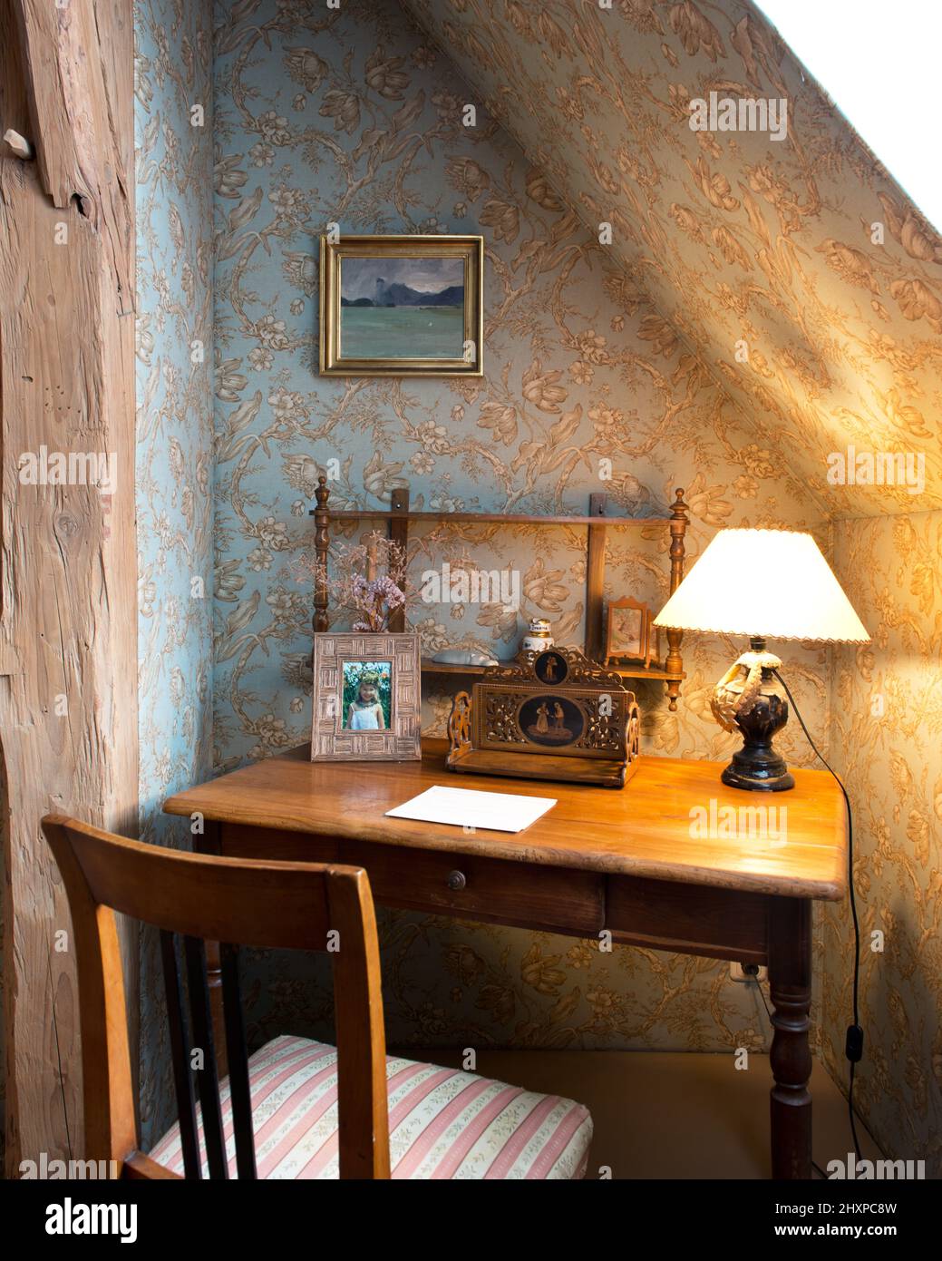 niche or alcove with blue and brown patterned wallpaper, old writing desk, table lamp, Biedermeier chair and painting Stock Photo