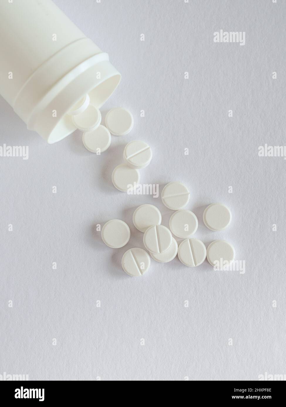 Dose with white pills on white background. Overhead view with copy space Stock Photo