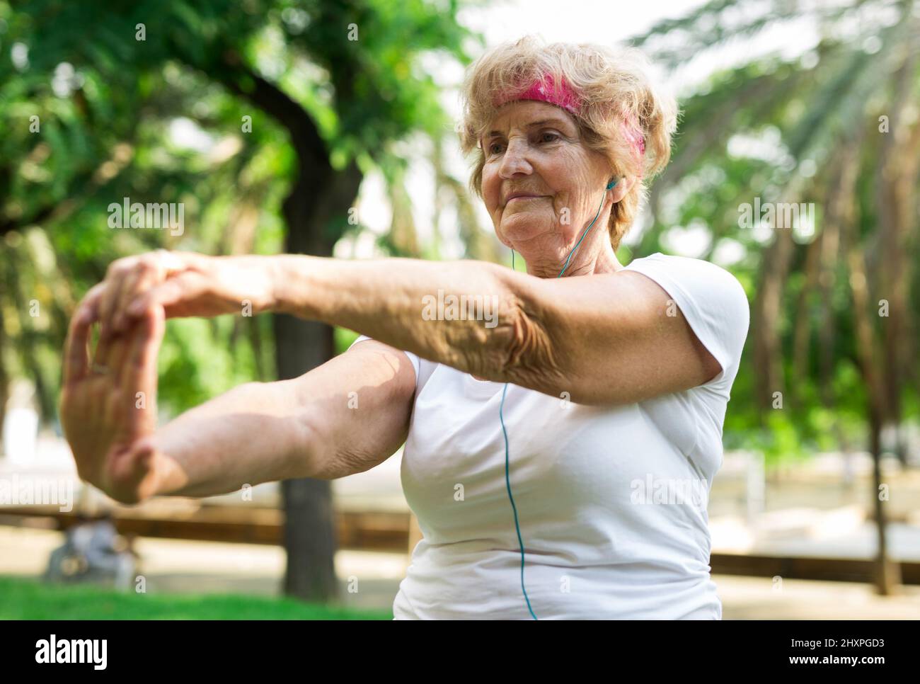 Old lady doing fitness exercises in park Stock Photo