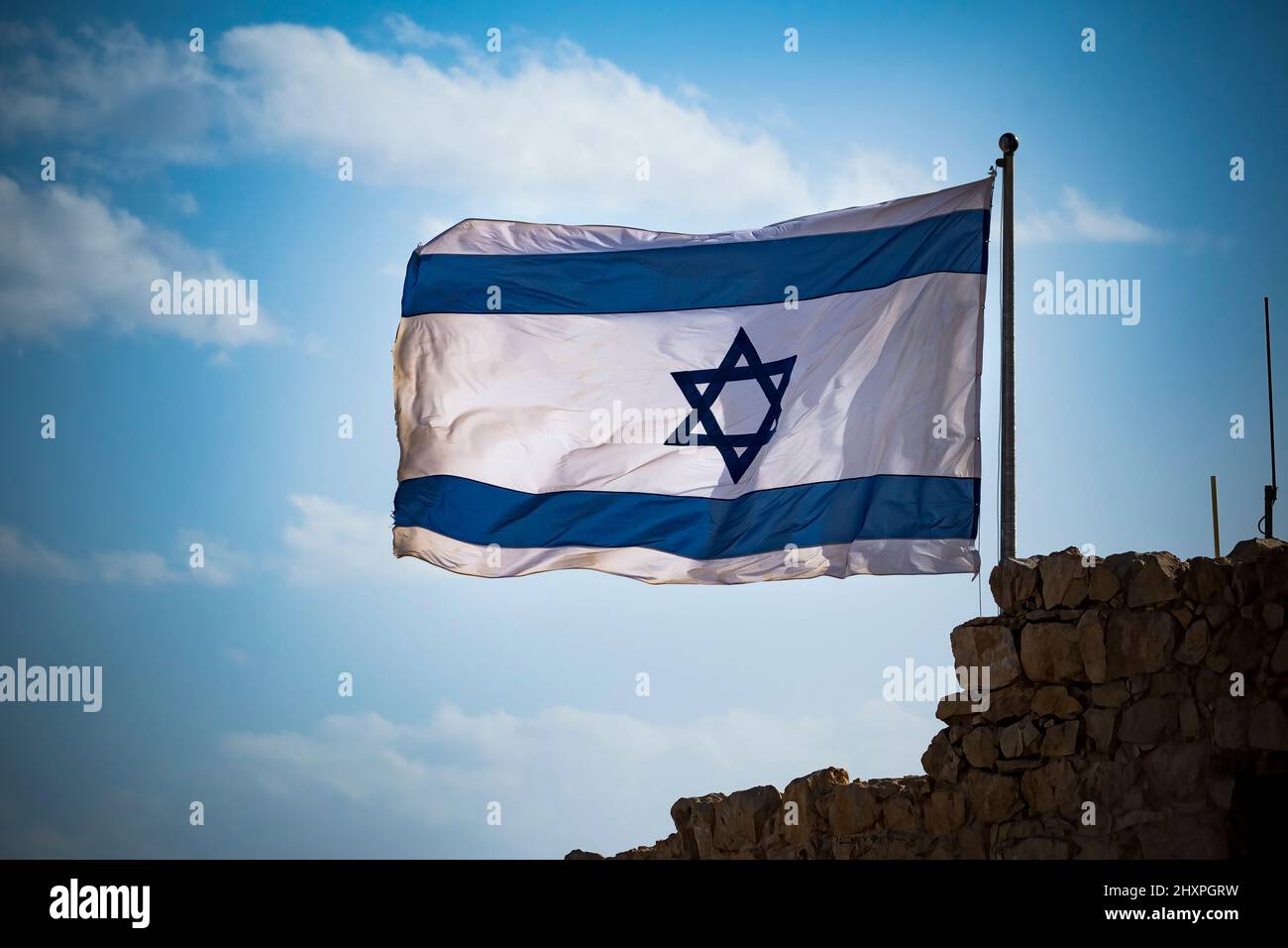Flag of Israel fluttering in strong wing against cloudy sky Stock Photo