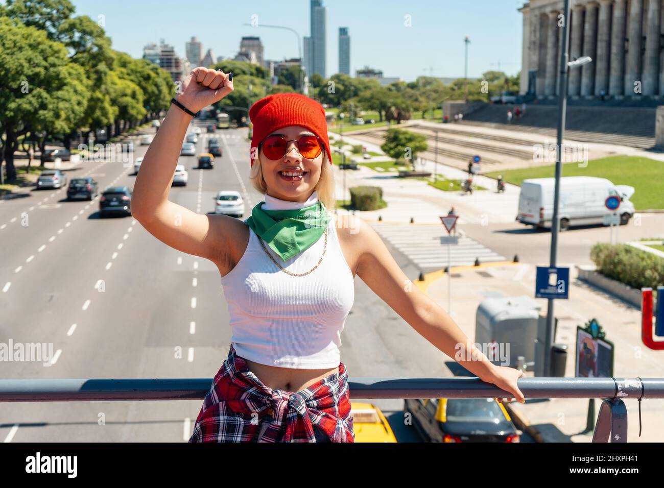Beautiful young woman with her fist raised with a green scarf symbolizing the feminist fight for equality and legal abortion in Latin America. Concept Stock Photo