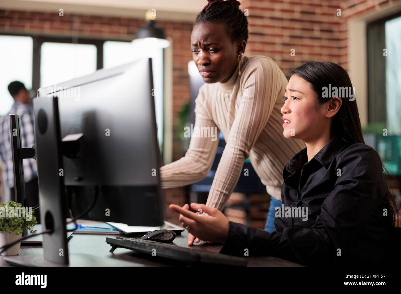 Mixed tech engineering team unsure about developed program result. Confused programmers questioning next move of artificial intelligence on database grid by using machine learning to defend system. Stock Photo