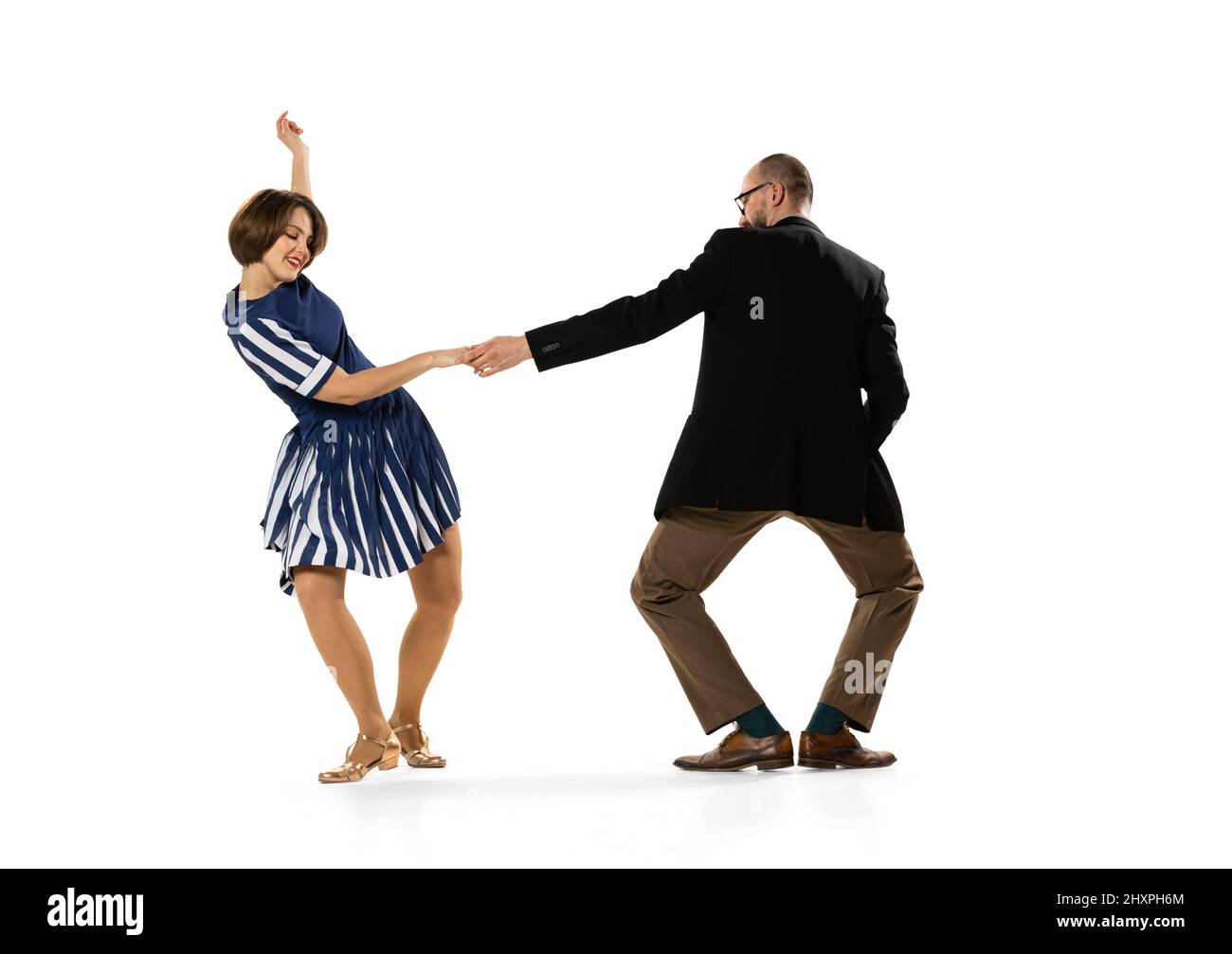 Happy young man and woman in vintage retro style outfits dancing lindy hop dance isolated on white background. Timeless traditions, 60s, 70s fashion Stock Photo