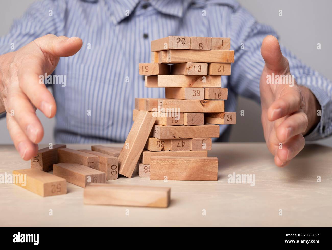 Falling wood blocks tower in businessman hands closeup. Economic crisis and failure in business concept. Risk management and strategic planning. High quality photo Stock Photo