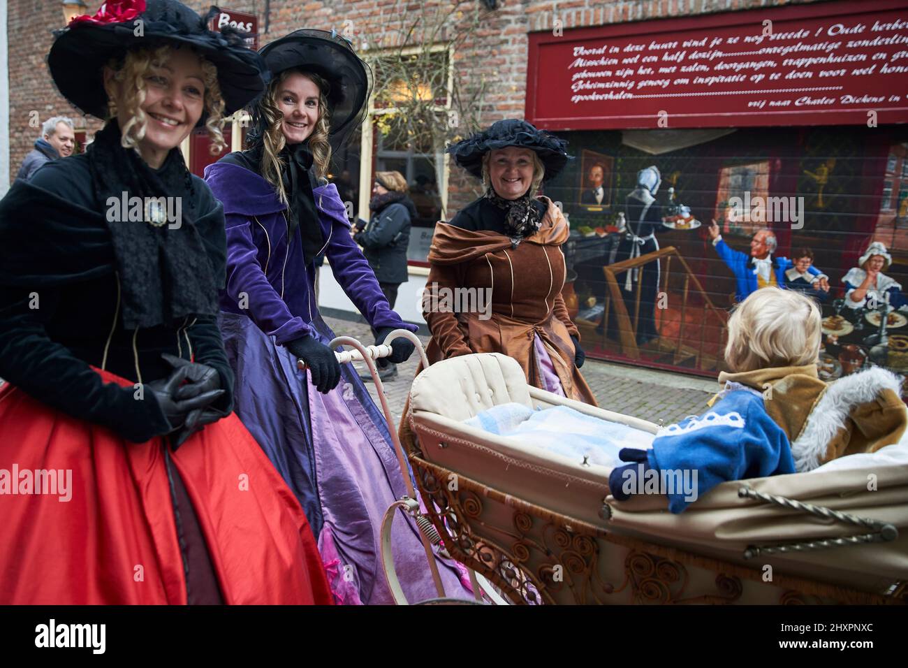 A group of participants walk around dressed in period costumes with an old baby carriage Stock Photo