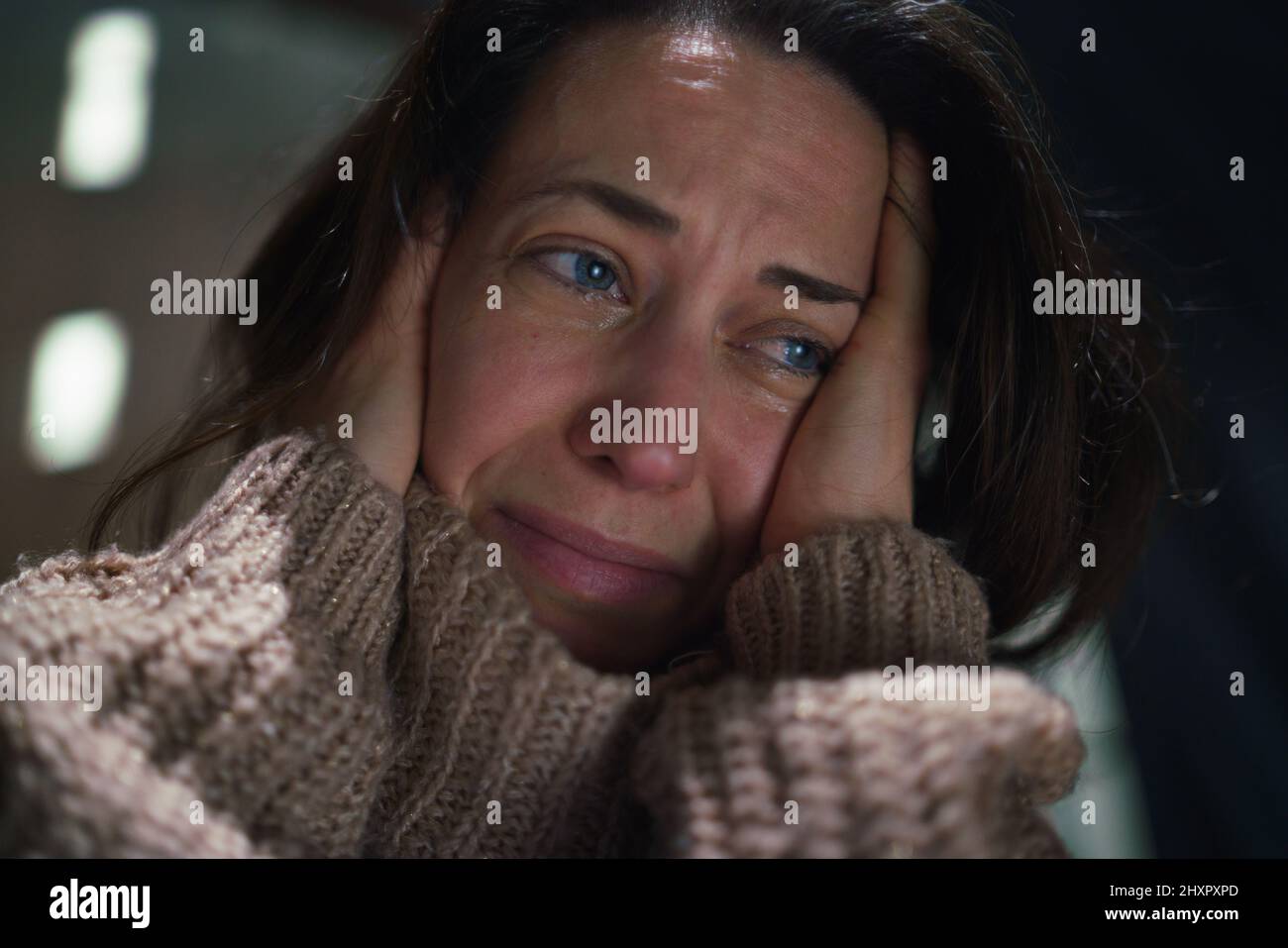 Close-up of depressed mid-adult lonely woman crying in the dark. Stock Photo