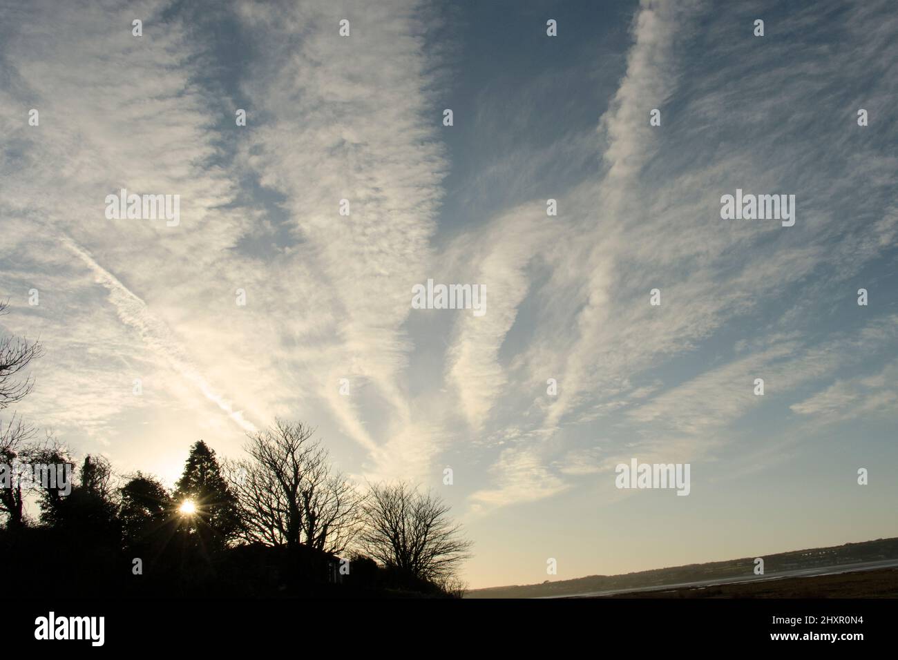 High Cirrus clouds are highlighted by the last light of day. The more linear features would have been seeded by high altitude jet contrails Stock Photo