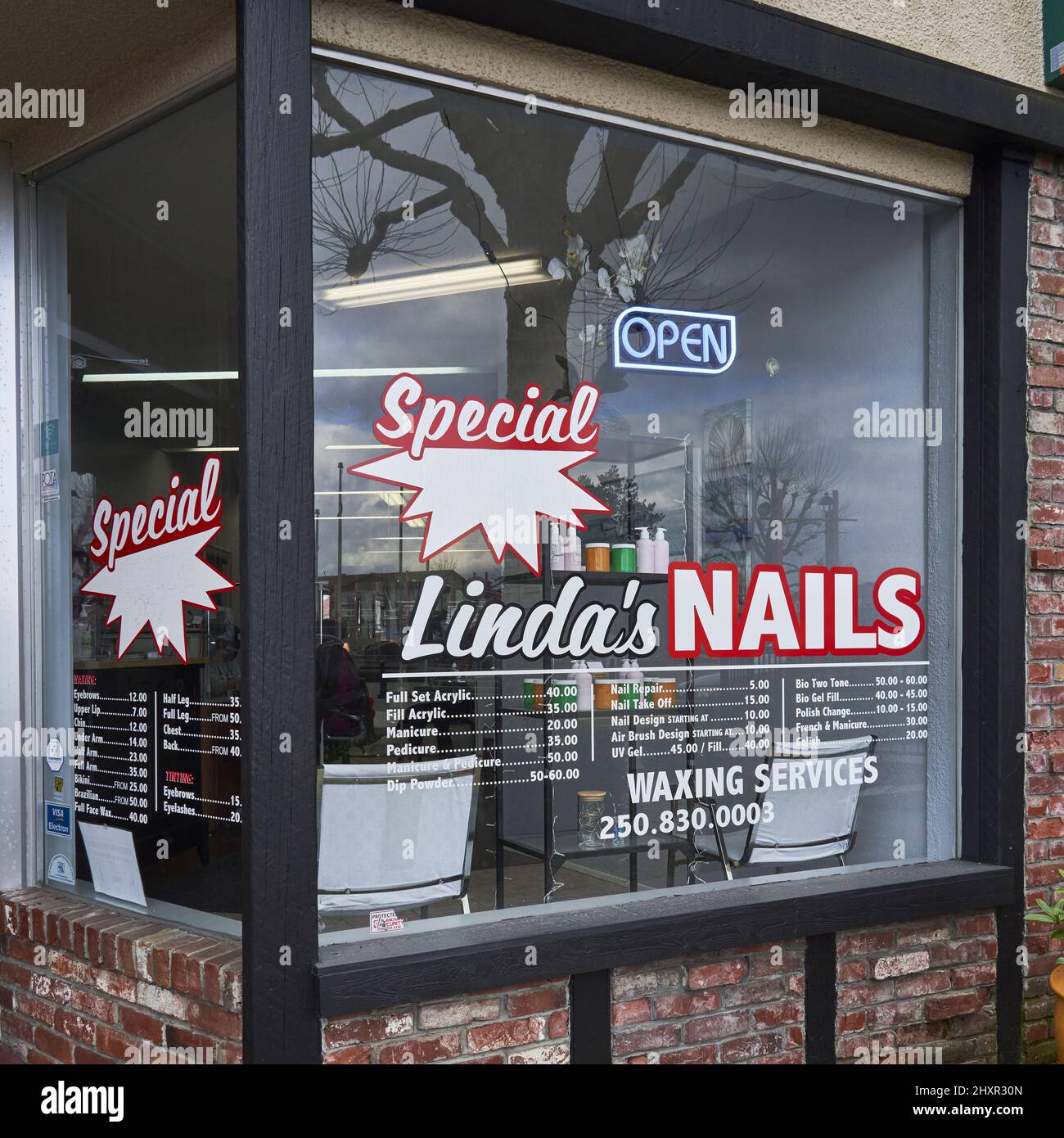 A nail salon window advertising it's services and prices with the