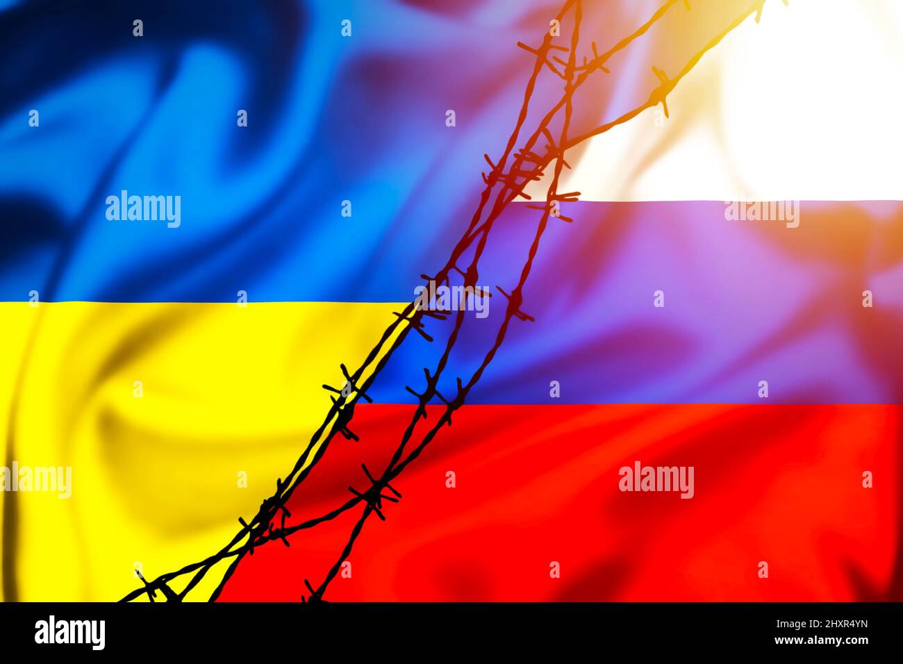 Silk flags of Russian Federation and Ukraine divided by barb wire sun haze illustration, concept of tense relations between Ukraine and Russia Stock Photo