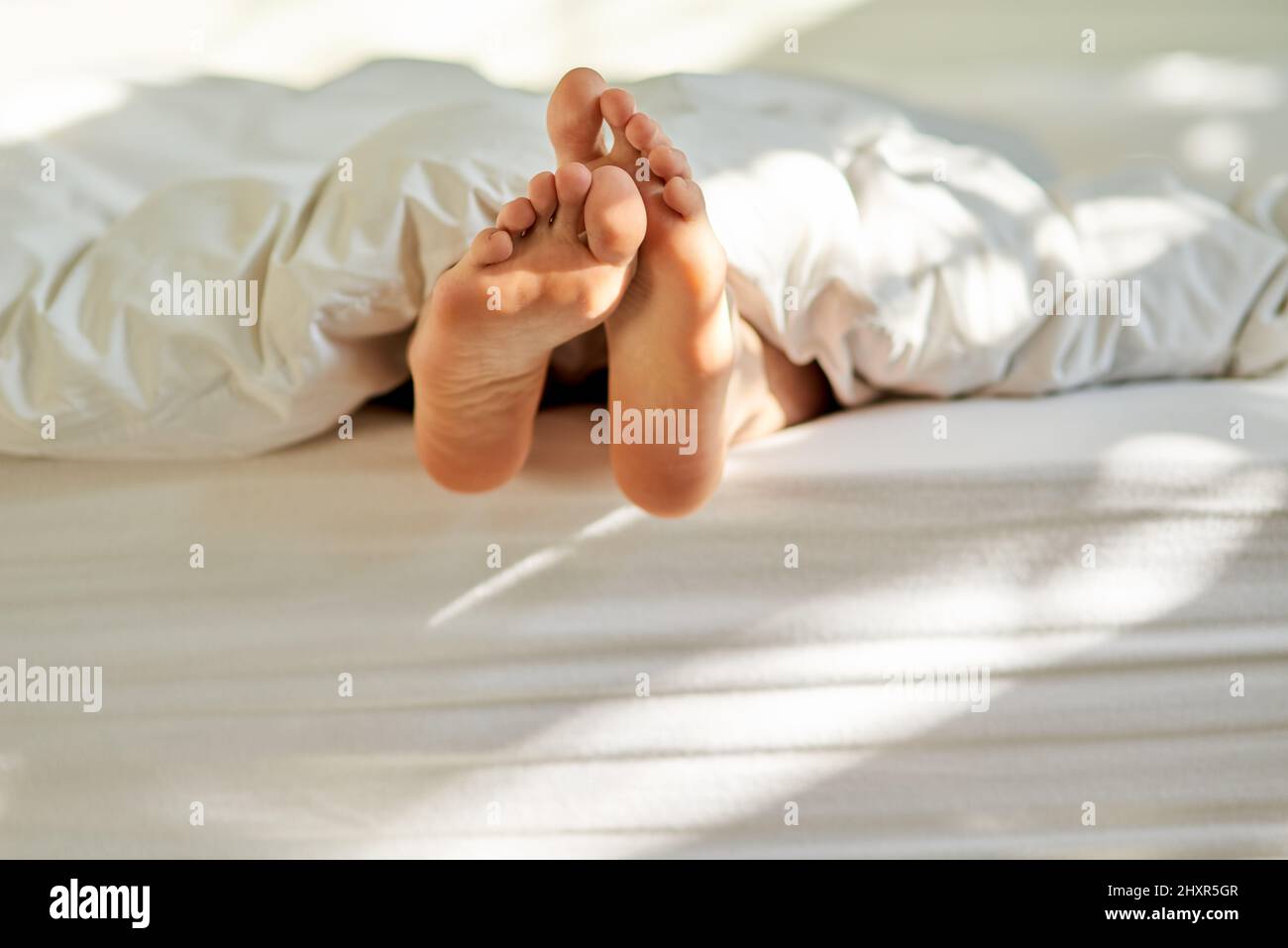 Wiggling toes of wakefulness. Shot of a mans feet poking out from the