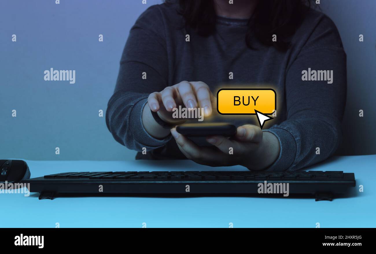 Woman shopping through smartphone on app. Buy button hologram screen. Mobile payment concept. Stock Photo