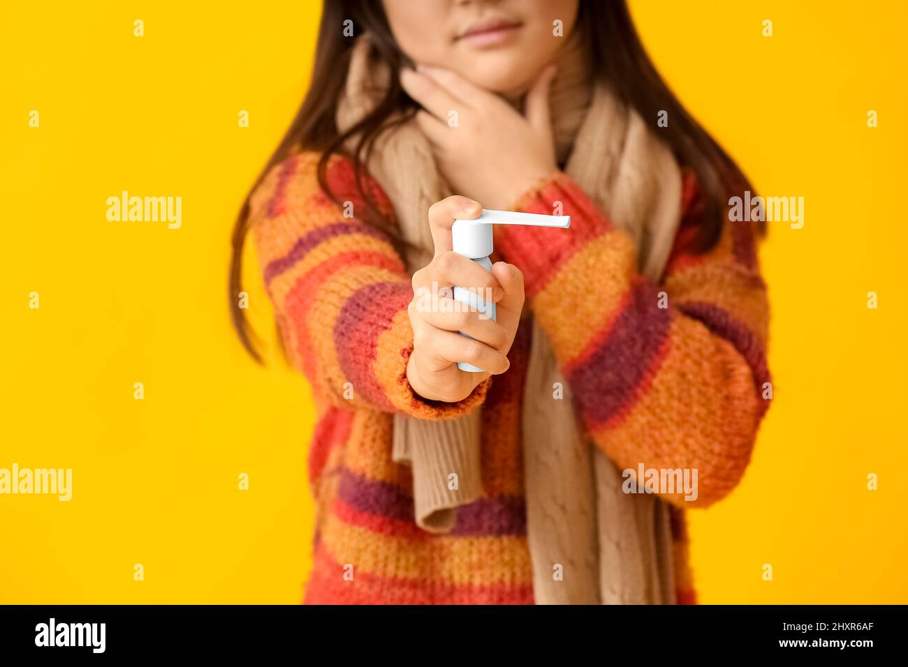 Ill girl with sore throat and inhaler on color background Stock Photo