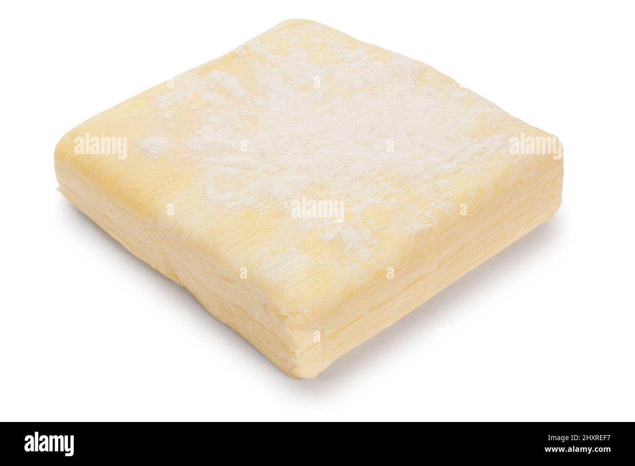 Studio shot of a block of uncooked puff pastry cut out against a white background - John Gollop Stock Photo