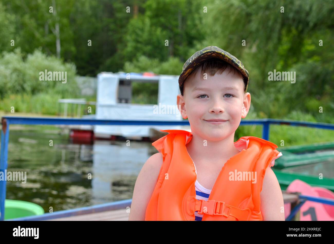 boy in a baseball cap and an orange inflatable life jacket against Stock Photo