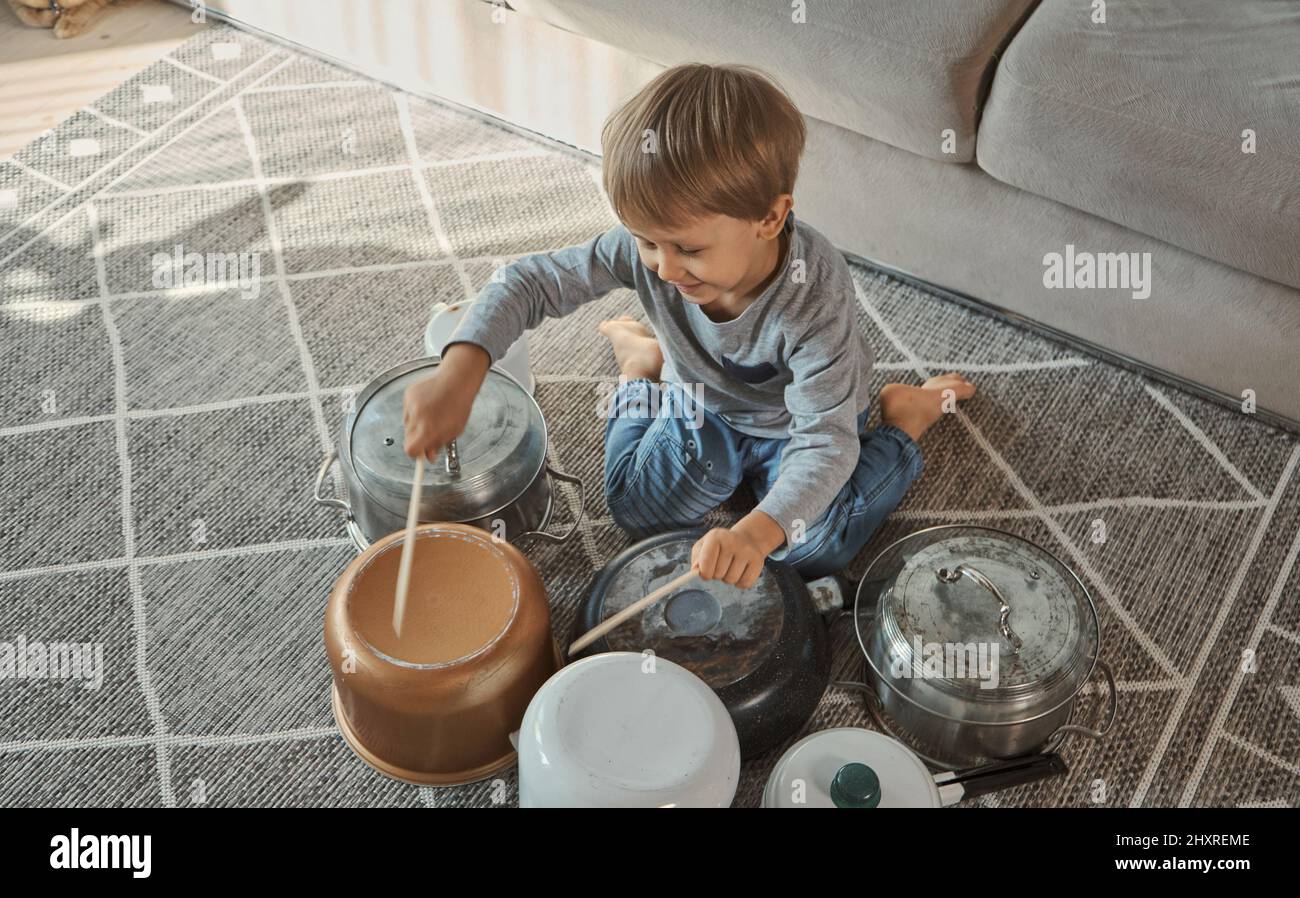 Child drummer having fun drum playing on kitchen pans at home Stock Photo