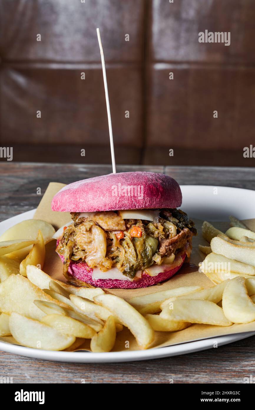 pink burger with Italian cassuola on a table in a restaurant. a traditional dish in a modern way with fries Stock Photo