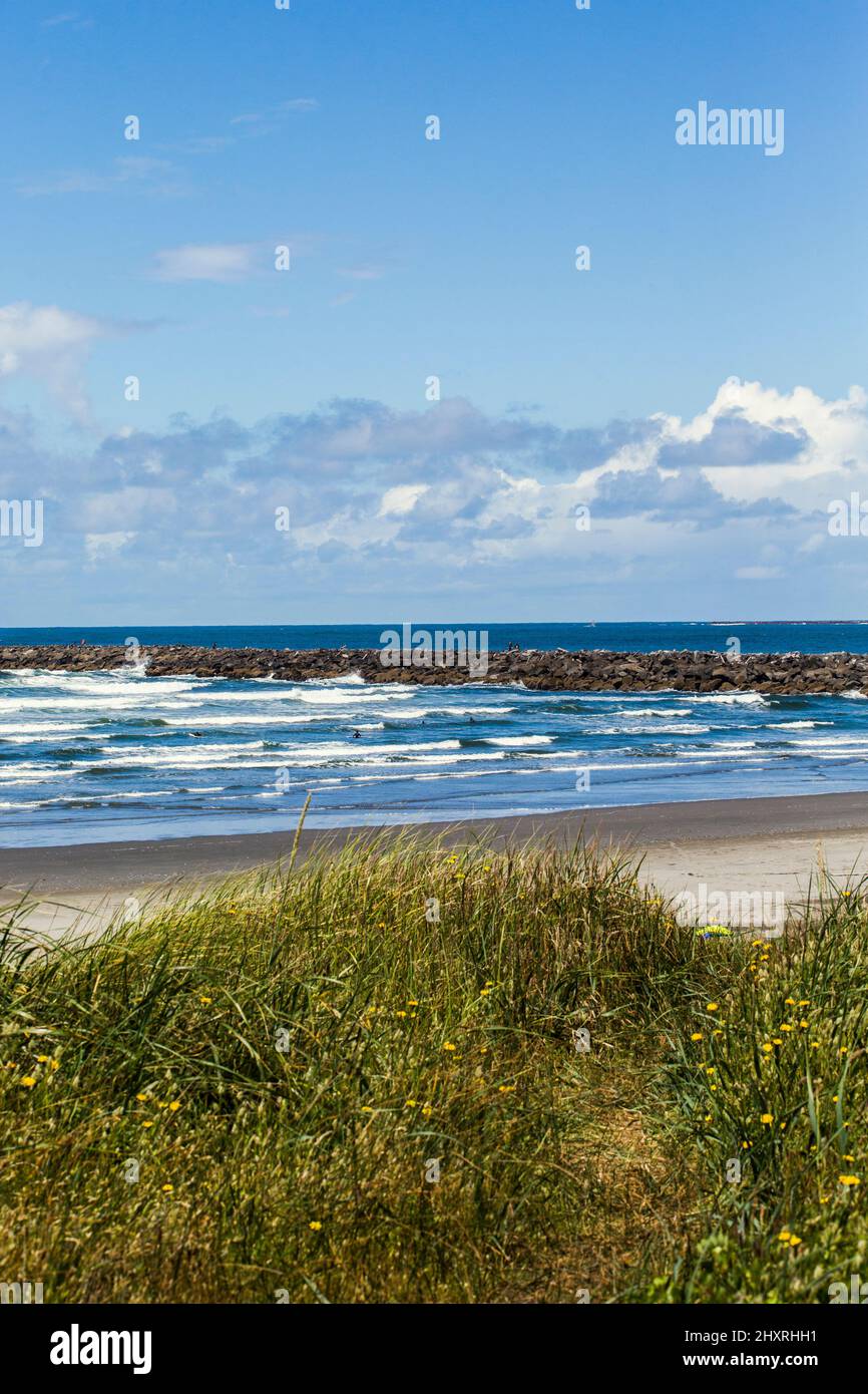 Empty beach with waves crashing and a seawall in distance Stock Photo
