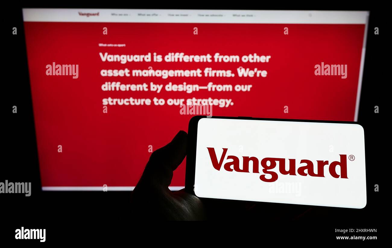 Person holding smartphone with logo of US financial company The Vanguard Group Inc. on screen in front of website. Focus on phone display. Stock Photo
