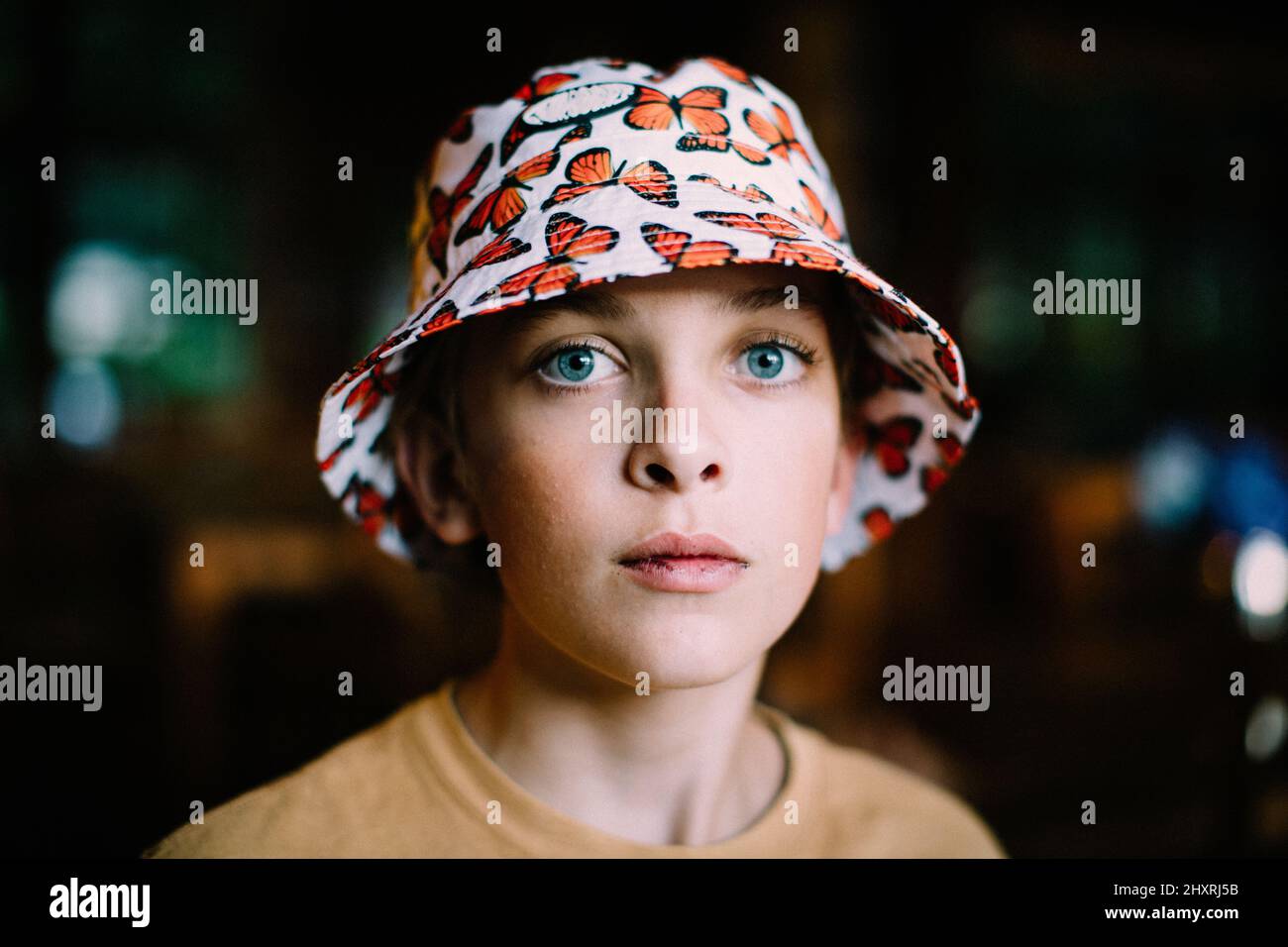 Close Up Portrait of Blue Eyed Boy in Butterfly Bucket Hat Stock Photo