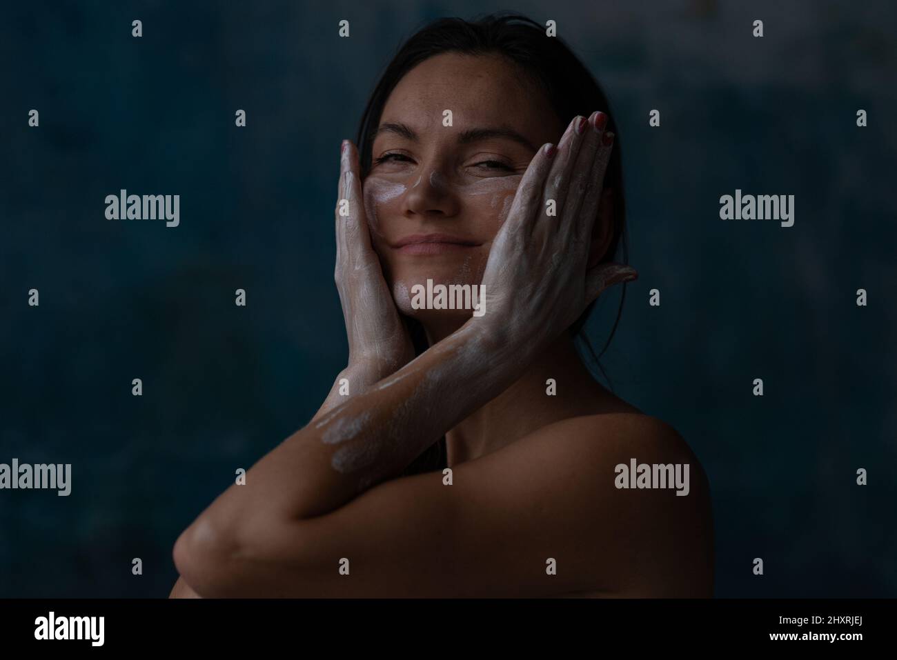 Woman drawing face by argil touching by hands and smiling Stock Photo