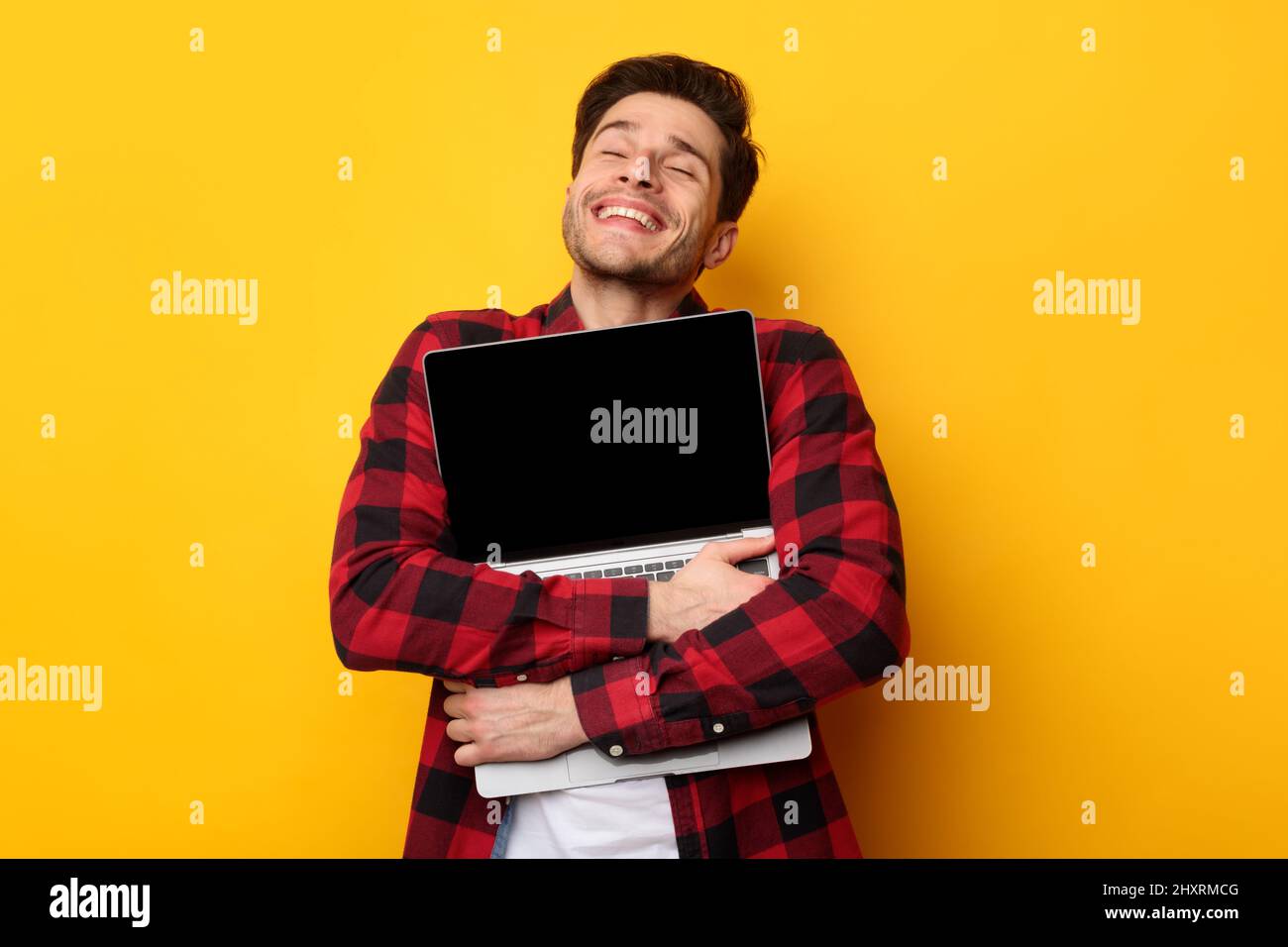 Technology Lover. Excited man hugging laptop at studio Stock Photo