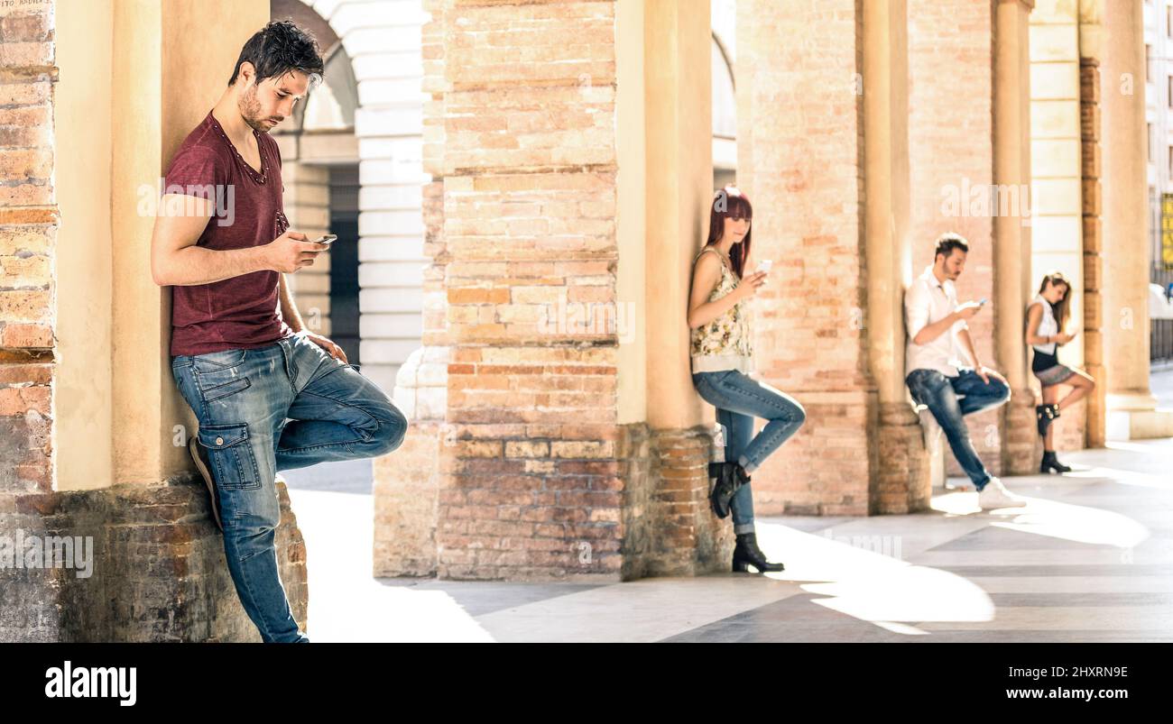 Young friends group using smartphone in urban city center - Technology and actual lifestyle with mutual disinterest towards each other - Tech addictio Stock Photo