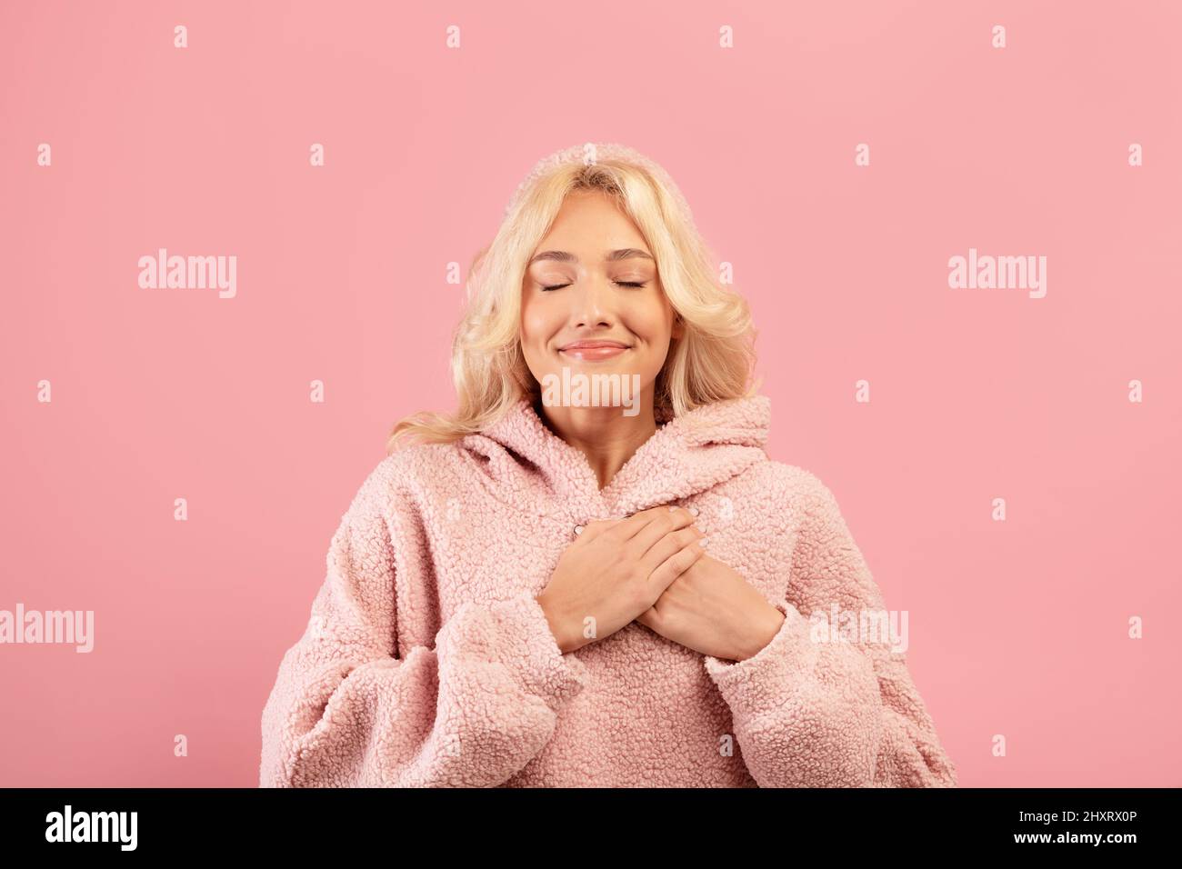 Gratitude concept. Thankful lady keeping palms on chest and smiling with closed eyes, expressing appreciation Stock Photo