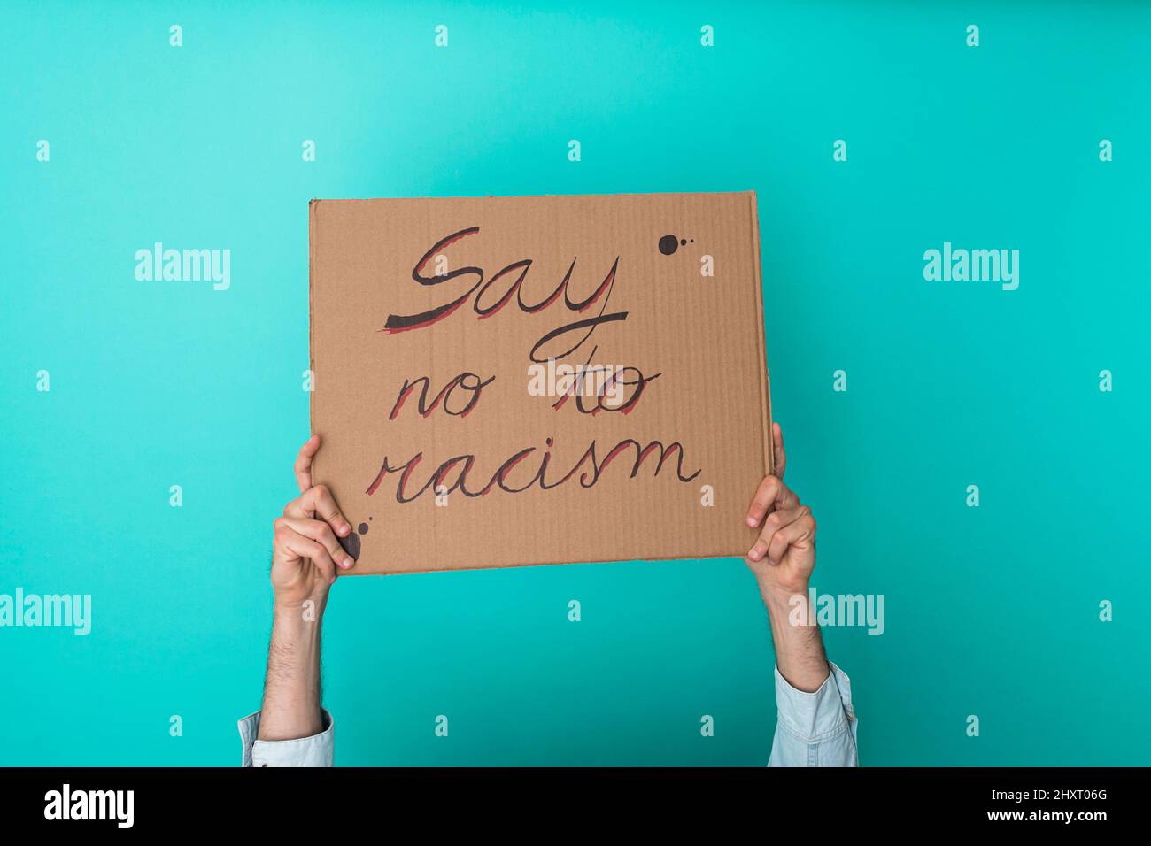 Crop anonymous person holding banner against racism over blue background - Equal rights concept Stock Photo