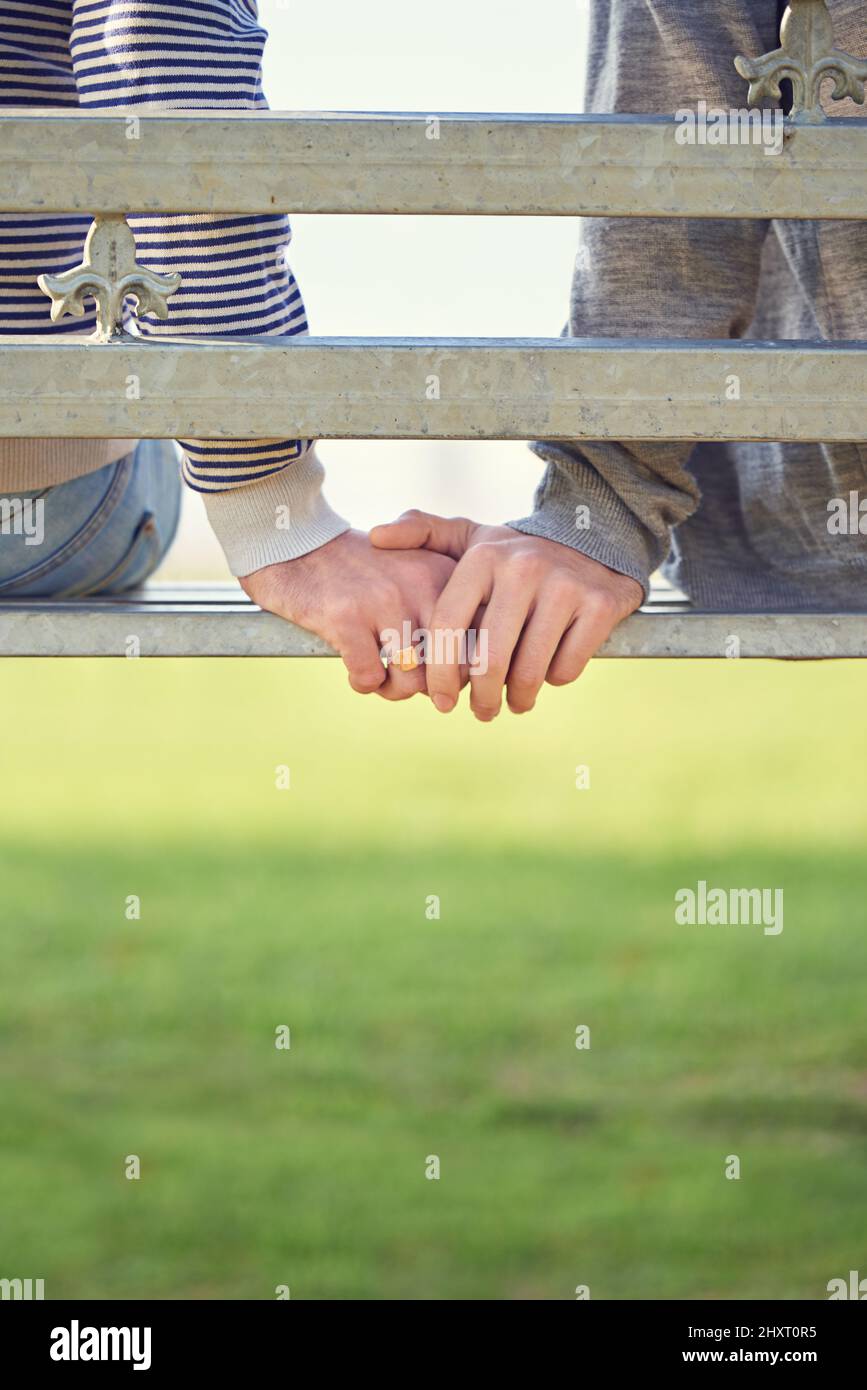 Always hand in hand. Rearview shot of a young gay couple sitting together on a park bench. Stock Photo