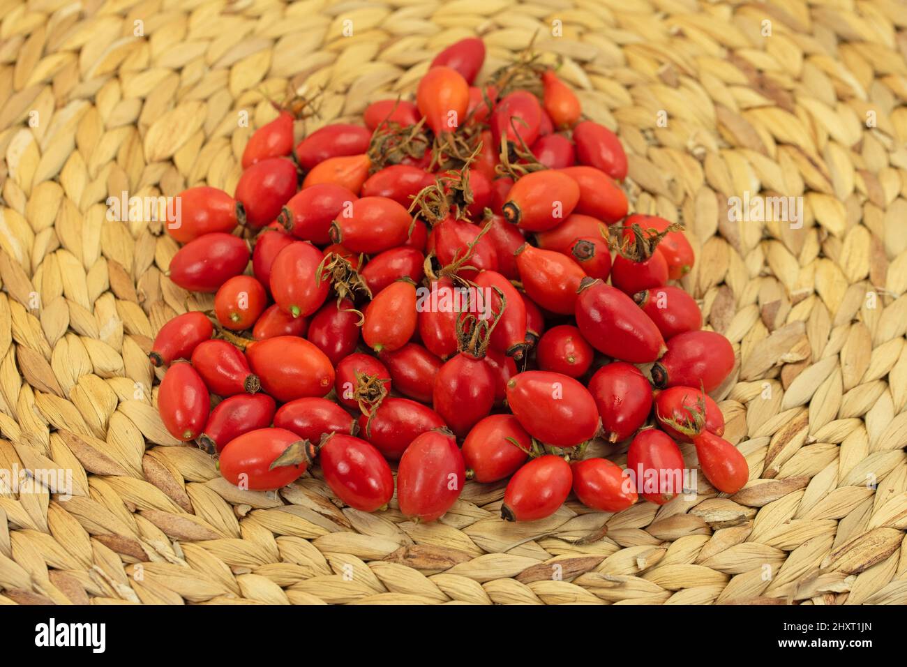 Ripe harvested rose hips on a bast bowl Stock Photo