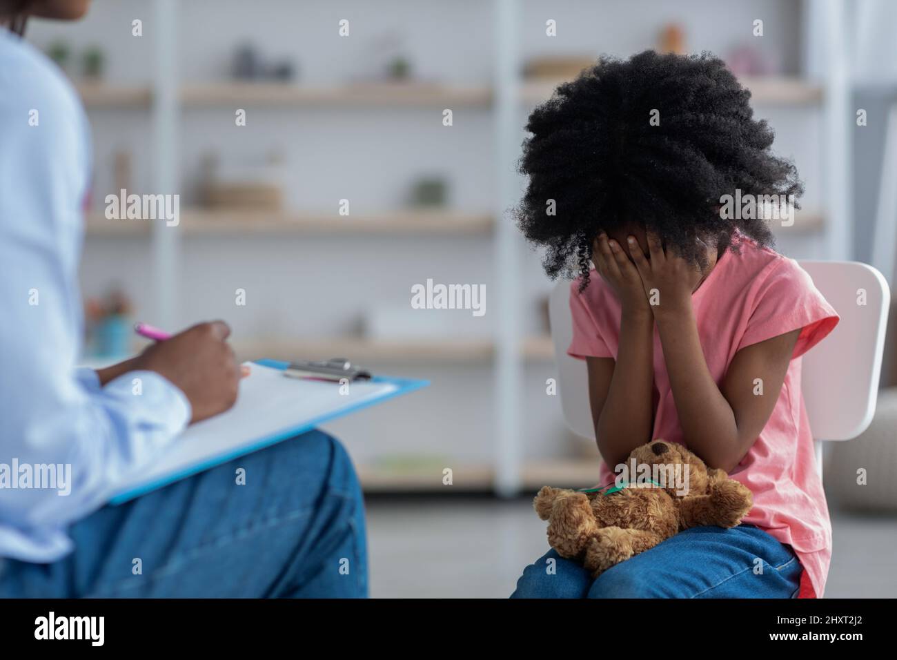 Upset little black kid crying at psychotherapy session Stock Photo