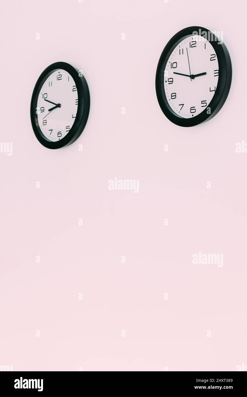 Vertical shot of two clocks hanging from the wall Stock Photo Alamy