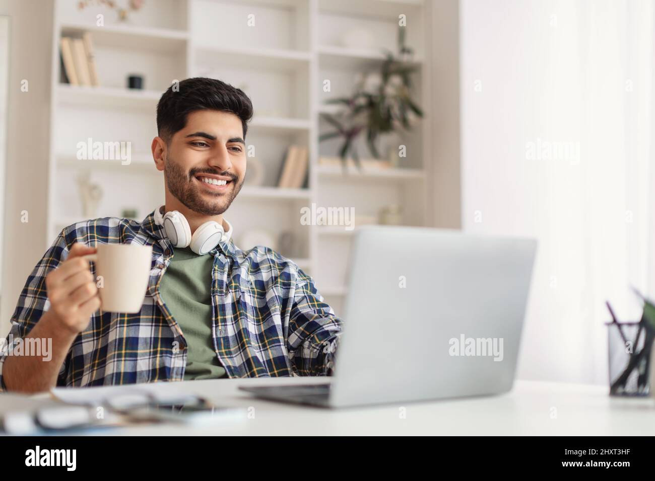 Arab man using laptop drinking coffee office Stock Photo