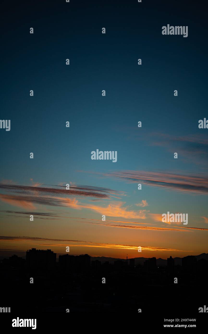 Vertical shot of a beautiful sunset over a the silhouettes of buildings ...