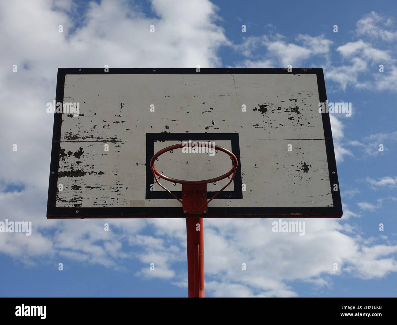 A photo of basketball hoop on an outdoor court with sky and clouds