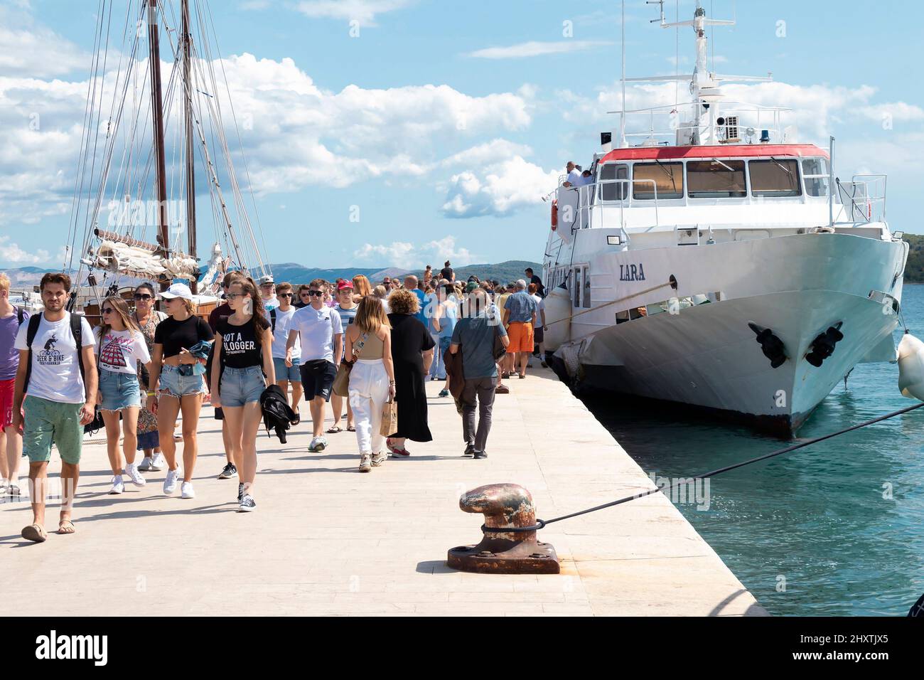 Vodice, Croatia - August 25, 2021: Young people walking away from moored Jadrolinija ship on the pier Stock Photo