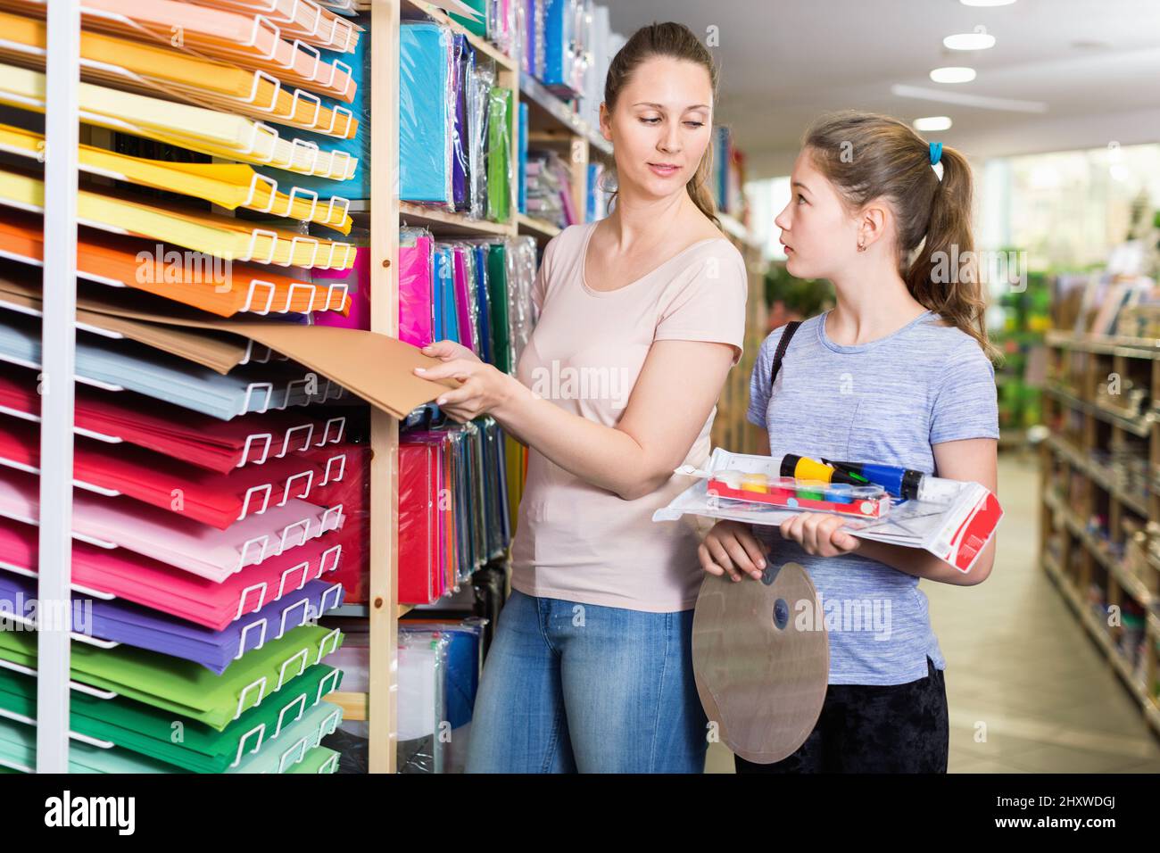 Happy preteen girl with her young mother buying school supplies in