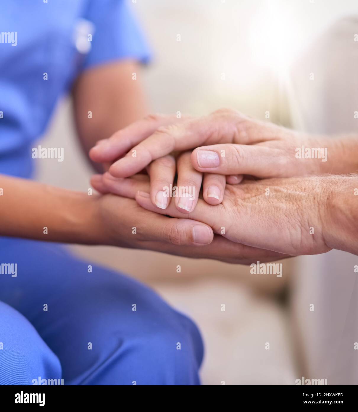Im here to help. Cropped shot of a nurse holding a senior womans hands in comfort. Stock Photo
